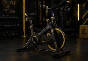 Bicicleta de spinning negra con detalles amarillos